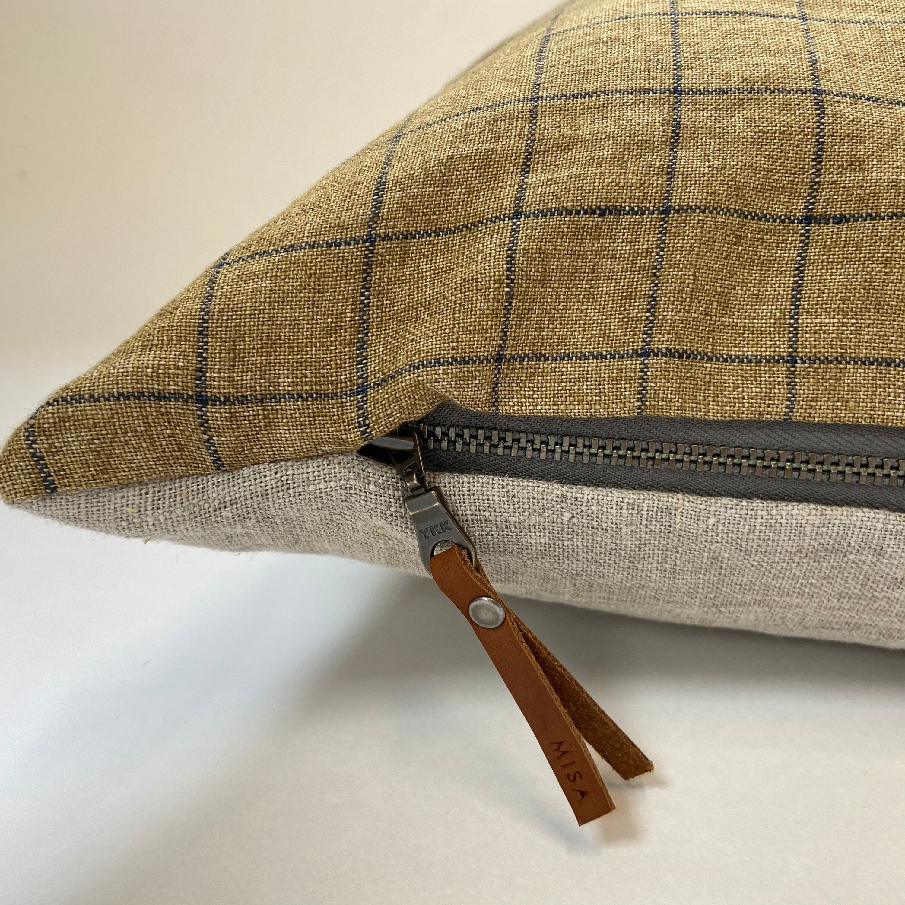 Plaid fabric pouch with a zipper on a light background Close-up of handmade natural linen pillow showing textured fabric weave and soft neutral tone, styled for minimalist home decor.