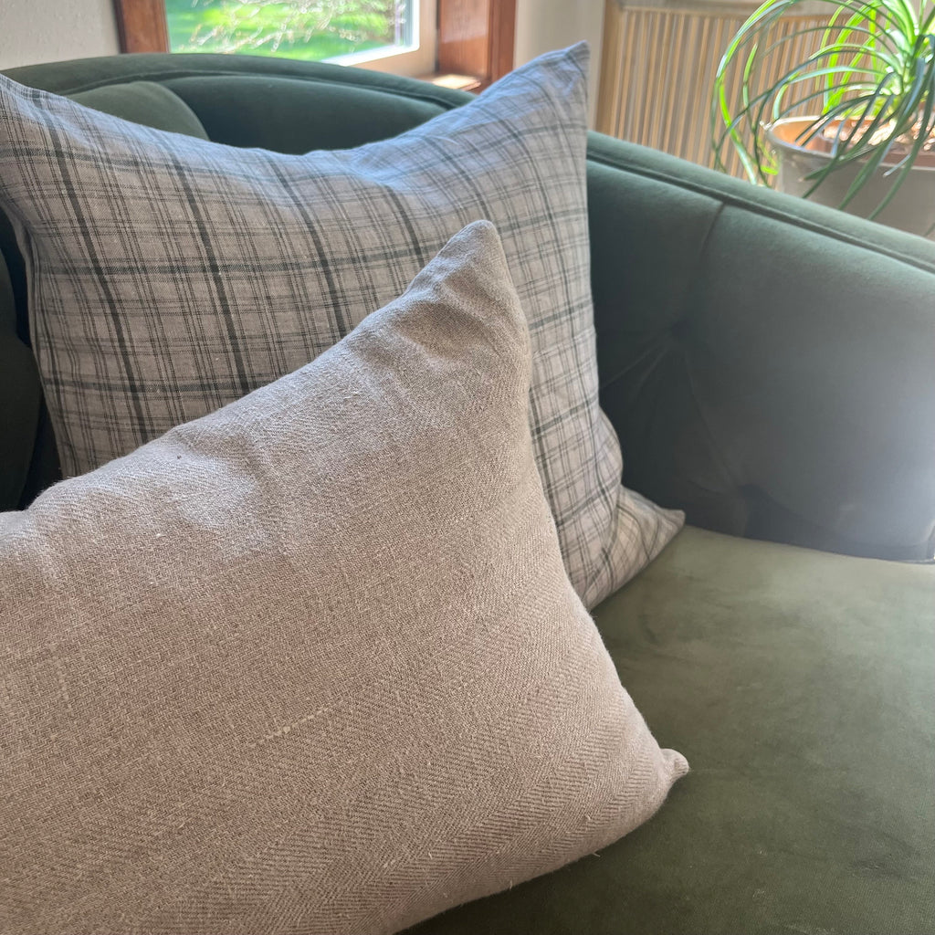 Striped linen pillow cover in soft pink, white, and tan displayed on a cozy neutral-toned sofa. The handcrafted texture and soothing colors enhance a warm, inviting living space, perfect for modern, boho, or coastal-style décor.