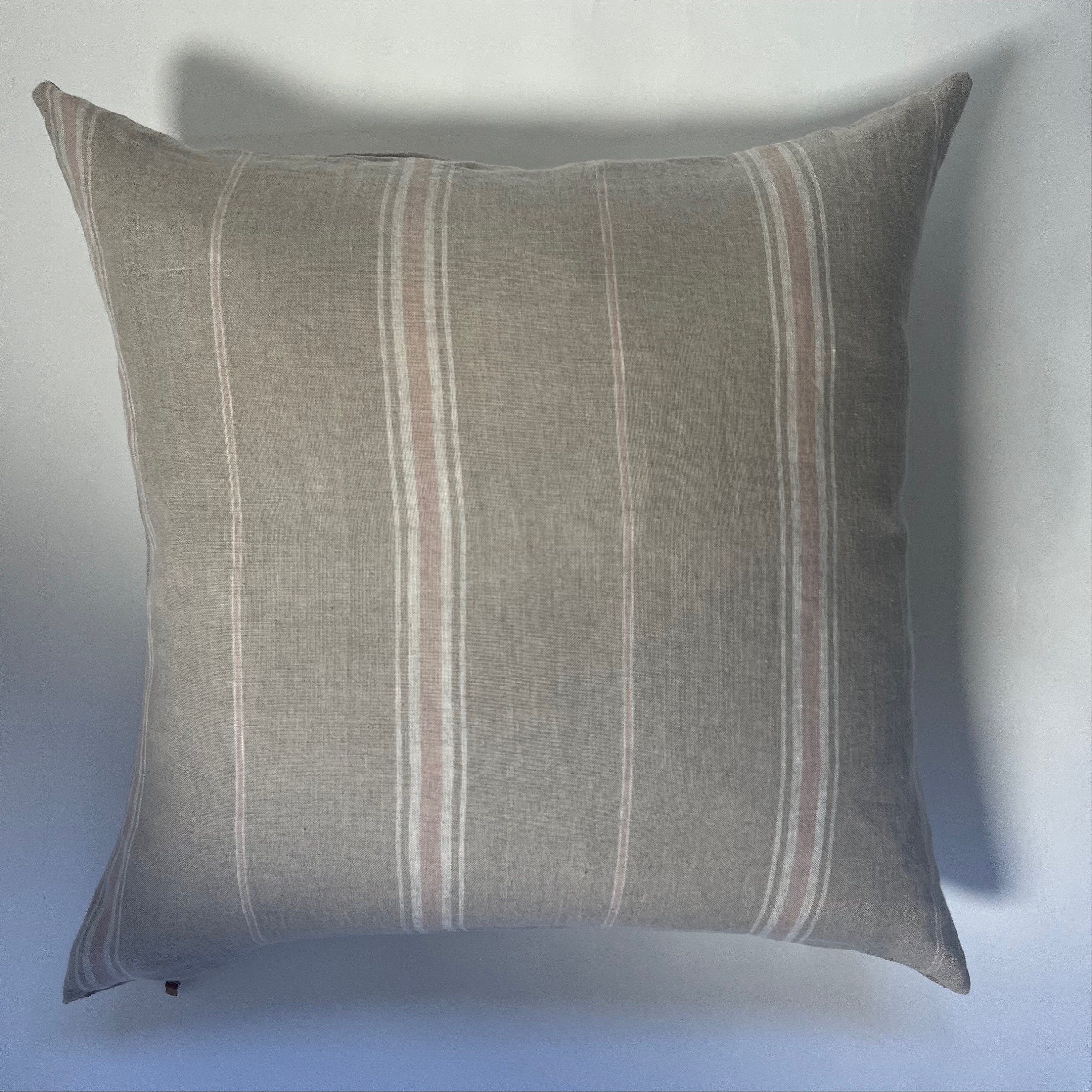 Close-up of the striped linen fabric highlighting the natural texture and soft hues. Pink, white, and tan threads are visible, showcasing artisanal stitching and breathable material.
